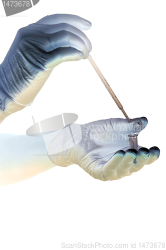 Image of Shaded hands in gloves hold pipette