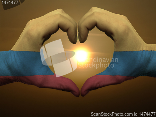 Image of Heart and love gesture by hands colored in columbia flag during 
