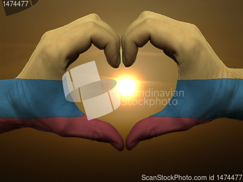 Image of Heart and love gesture by hands colored in columbia flag during 