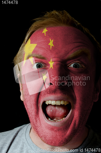 Image of Face of crazy angry man painted in colors of Chna flag