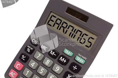 Image of Old calculator on white background showing text "earnings" in pe