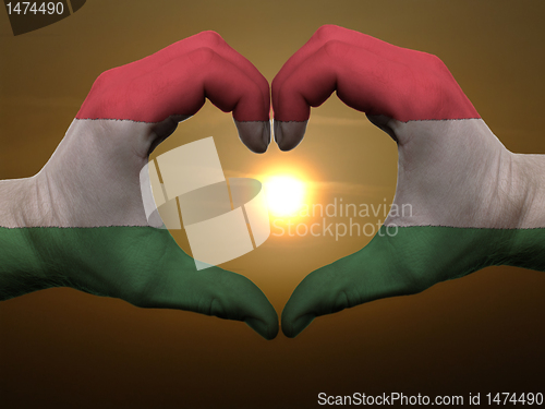 Image of Heart and love gesture by hands colored in hungary flag during b