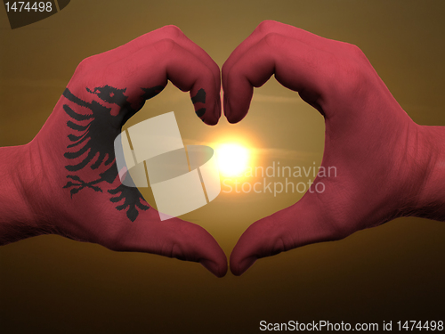 Image of Heart and love gesture by hands colored in albania flag during b