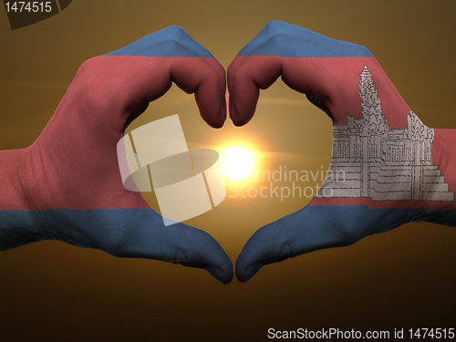 Image of Heart and love gesture by hands colored in cambodia flag during 