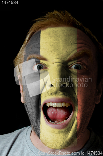 Image of Face of crazy angry man painted in colors of Belgium flag