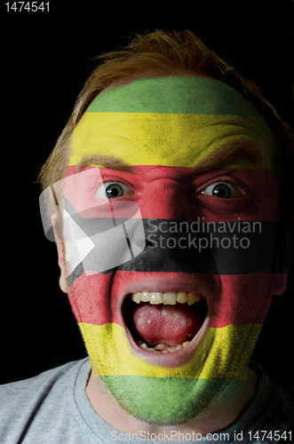 Image of Face of crazy angry man painted in colors of zimbabwe flag