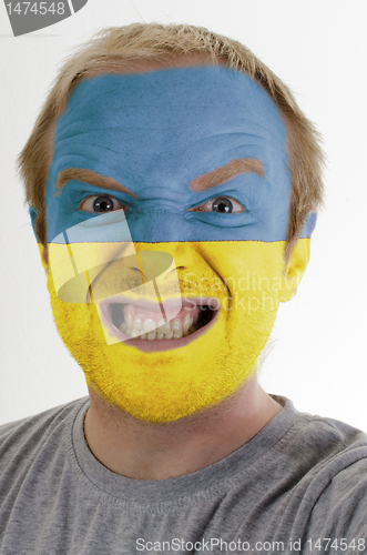 Image of Face of crazy angry man painted in colors of Ukraine flag