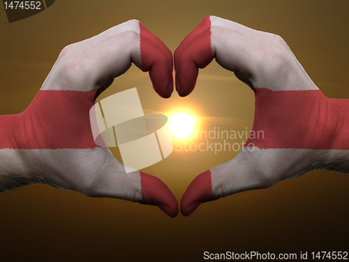 Image of Heart and love gesture by hands colored in england flag during b