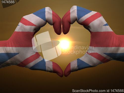 Image of Heart and love gesture by hands colored in uk flag during beauti