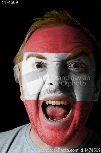 Image of Face of crazy angry man painted in colors of austria flag