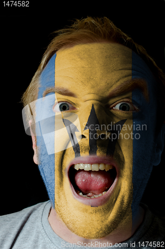 Image of Face of crazy angry man painted in colors of Barbados flag