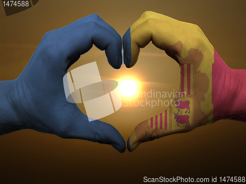Image of Heart and love gesture by hands colored in andora flag during be