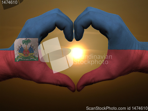 Image of Heart and love gesture by hands colored in haiti flag during bea