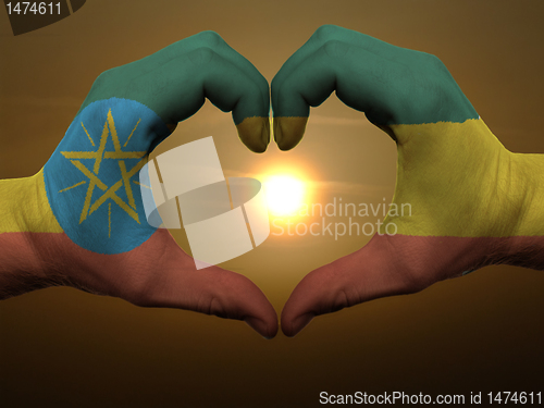 Image of Heart and love gesture by hands colored in ethiopia flag during 