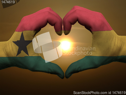 Image of Heart and love gesture by hands colored in ghana flag during bea