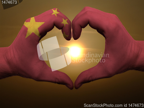 Image of Heart and love gesture by hands colored in china flag during bea