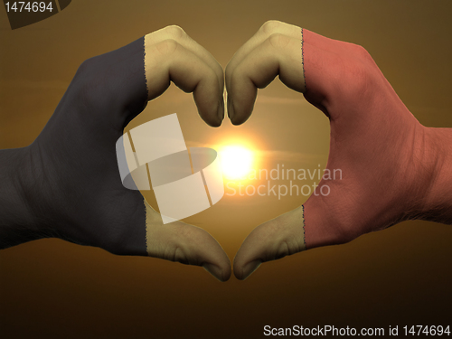 Image of Heart and love gesture by hands colored in belgium flag during b