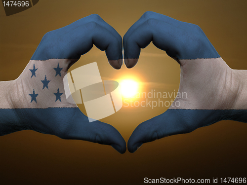 Image of Heart and love gesture by hands colored in honduras flag during 