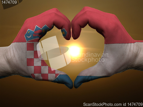 Image of Heart and love gesture by hands colored in croatia flag during b