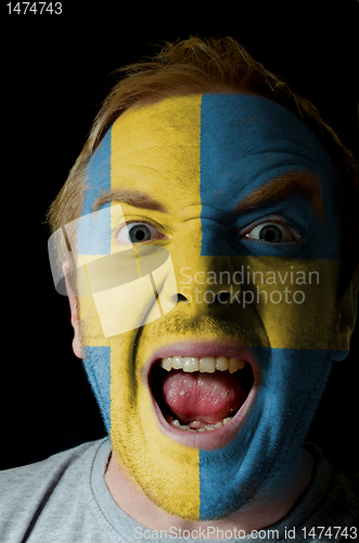 Image of Face of crazy angry man painted in colors of sweden flag
