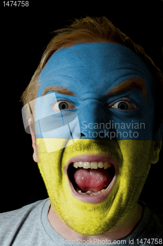 Image of Face of crazy angry man painted in colors of ukraine flag