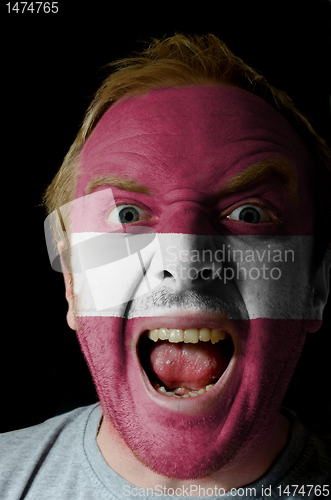 Image of Face of crazy angry man painted in colors of latvia flag