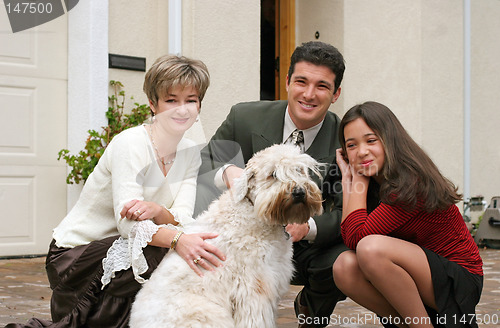 Image of Happy family with a dog in front of the home