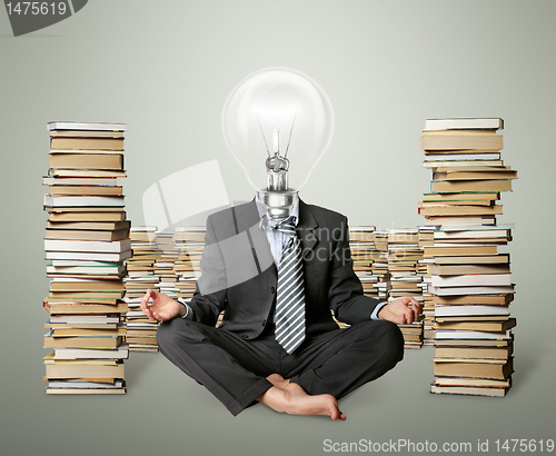 Image of businessman in lotus pose and lamp-head with many books near