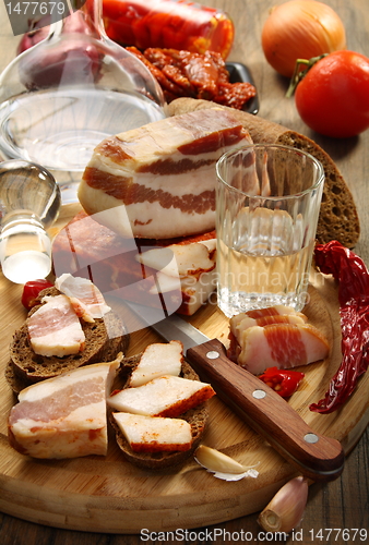 Image of Glass of vodka, bacon on rye bread.