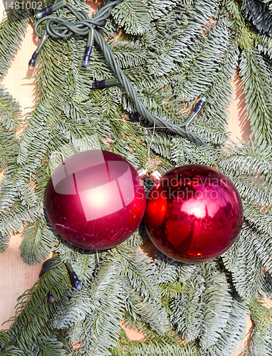 Image of Cristmas tree branch imitation and red toys pair.