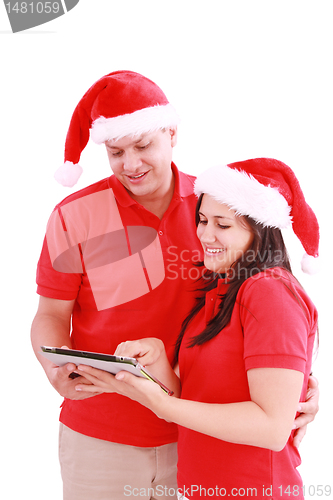 Image of Happy Christmas couple looking a tablet computer. Isolated on wh