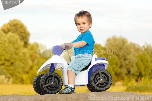 Image of Little boy sitting on toy quad