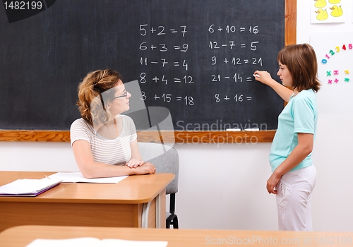 Image of Schoolgirl solving math equations at chalkboard