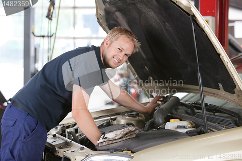 Image of Smiling mechanic working on car