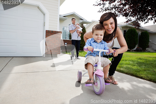Image of Loving Mother Teaching Son To Ride Tricycle