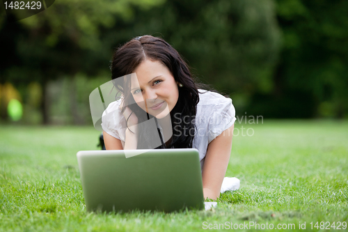 Image of Pretty female lying on grass With laptop