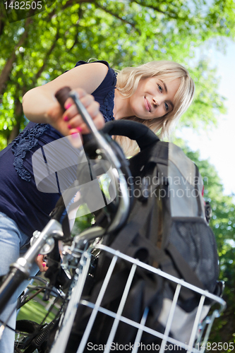 Image of Cute female student standing with her bike