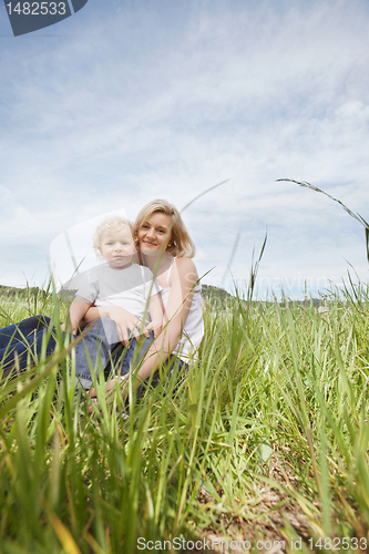 Image of Mother sitting on grass with son