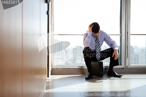 Image of Upset Business man Sitting on Briefcase