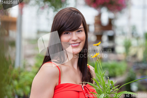 Image of Smiling woman holding flower pot