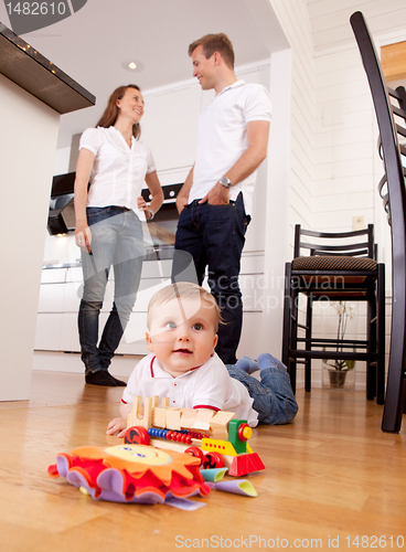 Image of Baby Playing on Floor with Parents in Background