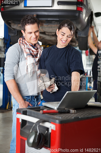 Image of Female mechanic using laptop with client