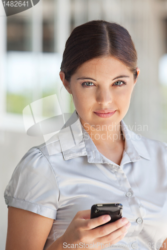 Image of Attractive businesswoman holding cell phone