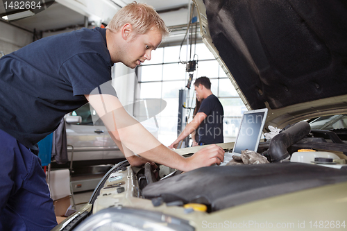 Image of Mechanic using laptop while working on car