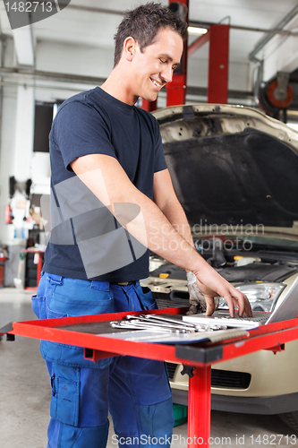 Image of Smiling young mechanic working on a laptop