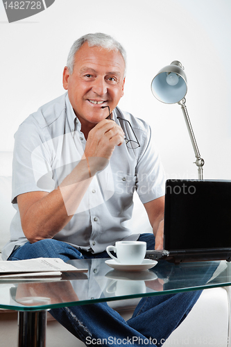 Image of Smiling Senior Man With Laptop on Table