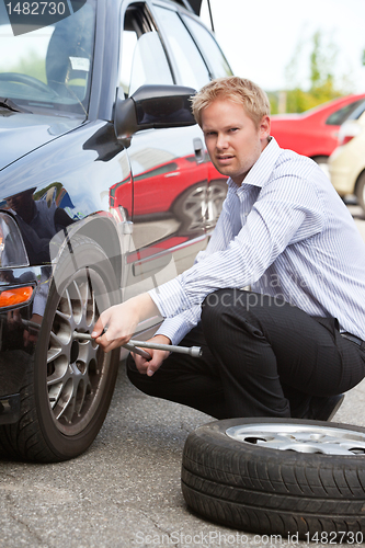 Image of Business Man Replacing Tire