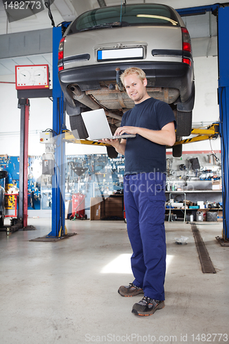 Image of Portrait of smiling mechanic working on laptop