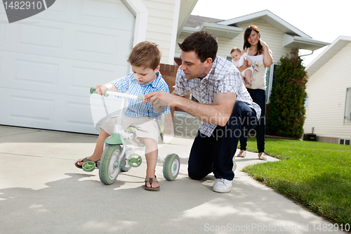 Image of Father Teaching Son To Ride Tricycle