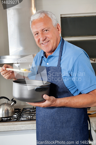 Image of Man Holding Spoon to Taste Food